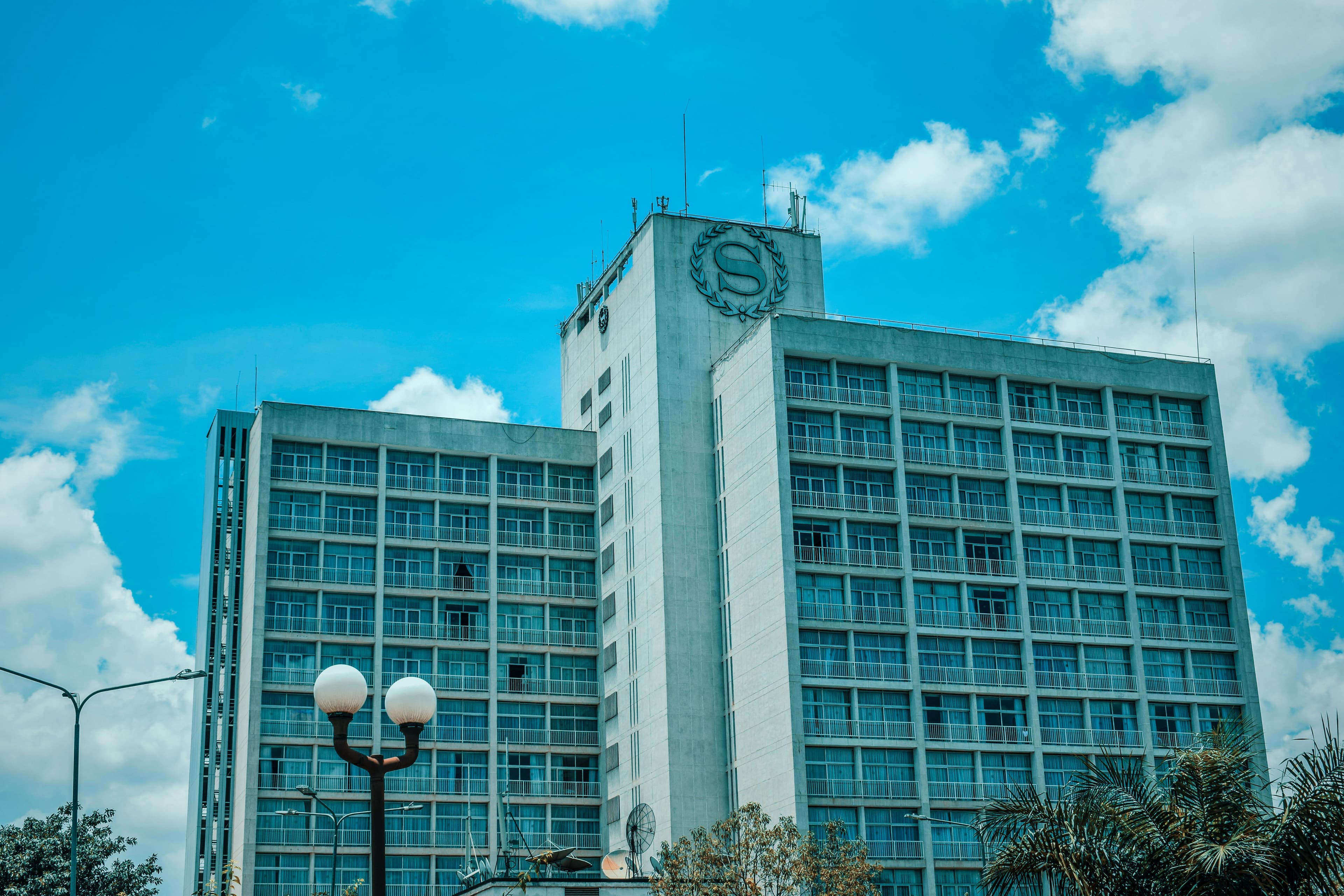 Modern Sheraton hotel building under a bright blue sky with white clouds.