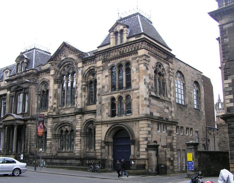 Grand historic stone building with ornate architecture, arched windows, and a dark blue door.