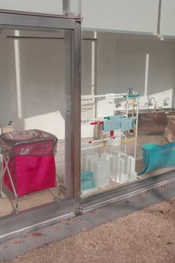 A pink cooler bag sits on a metal cart next to a large glass window.