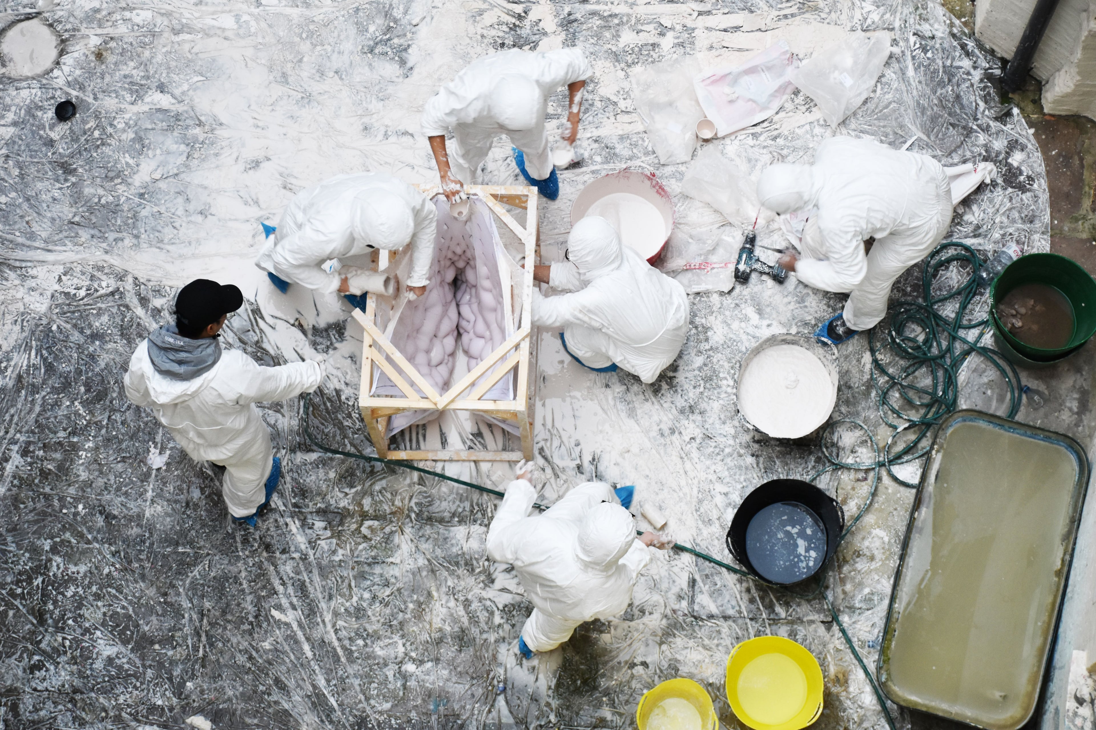 Six students in protective overalls in workshop