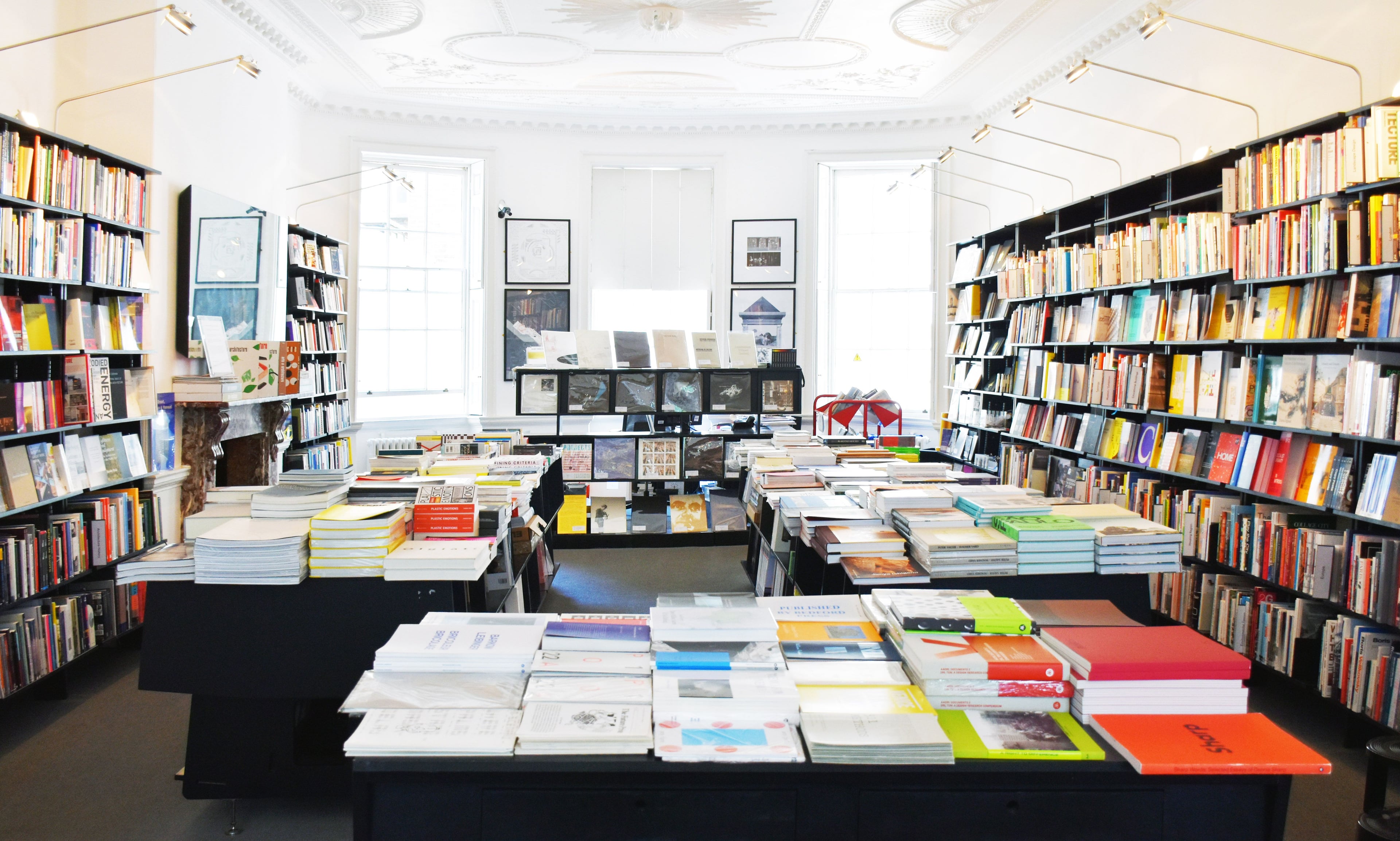 Photograph of a bookshop with tables stacked with books in the centre