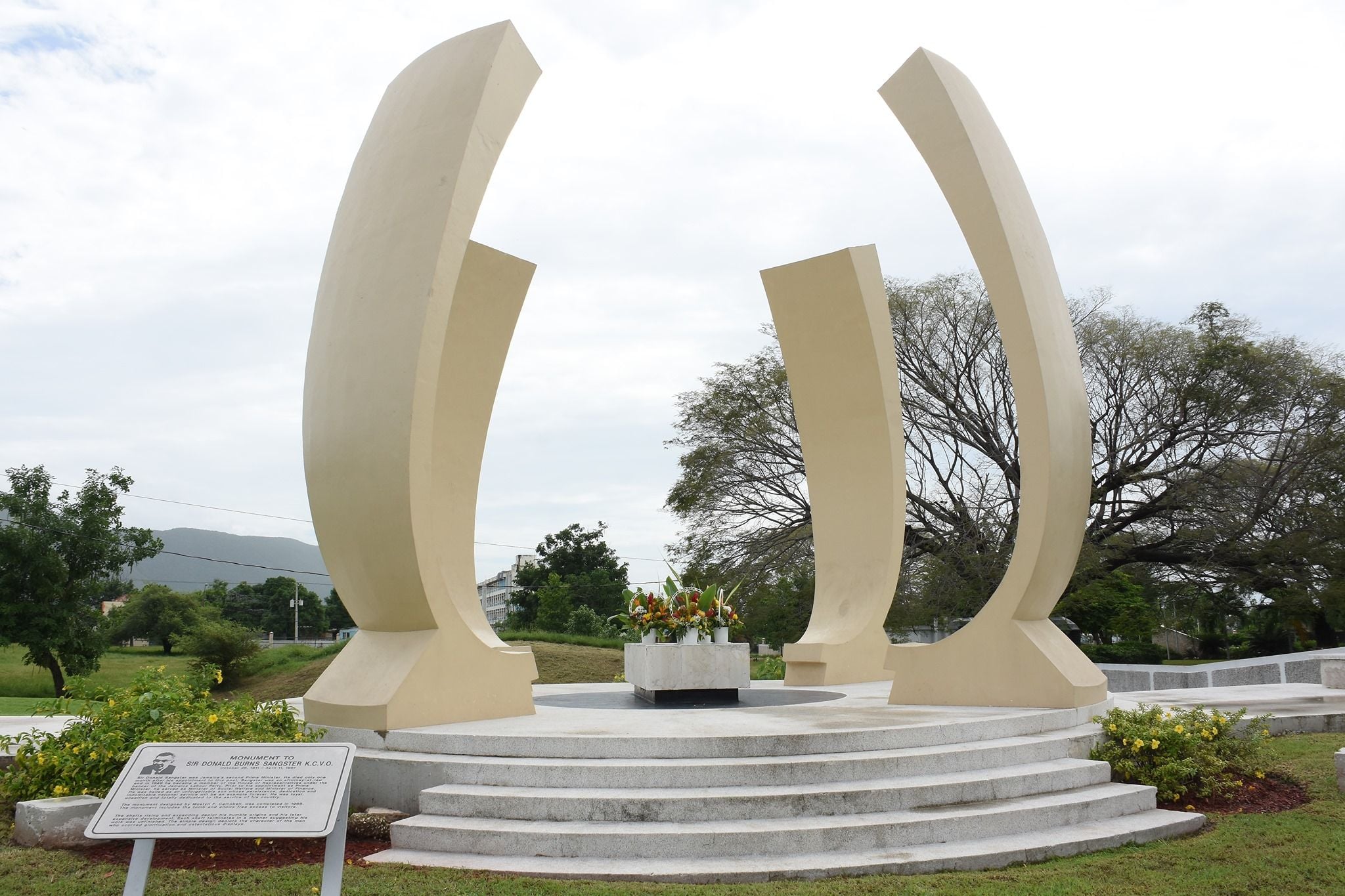 Monument with large, curved, light-colored pillars surrounding a central structure on a raised platform.
