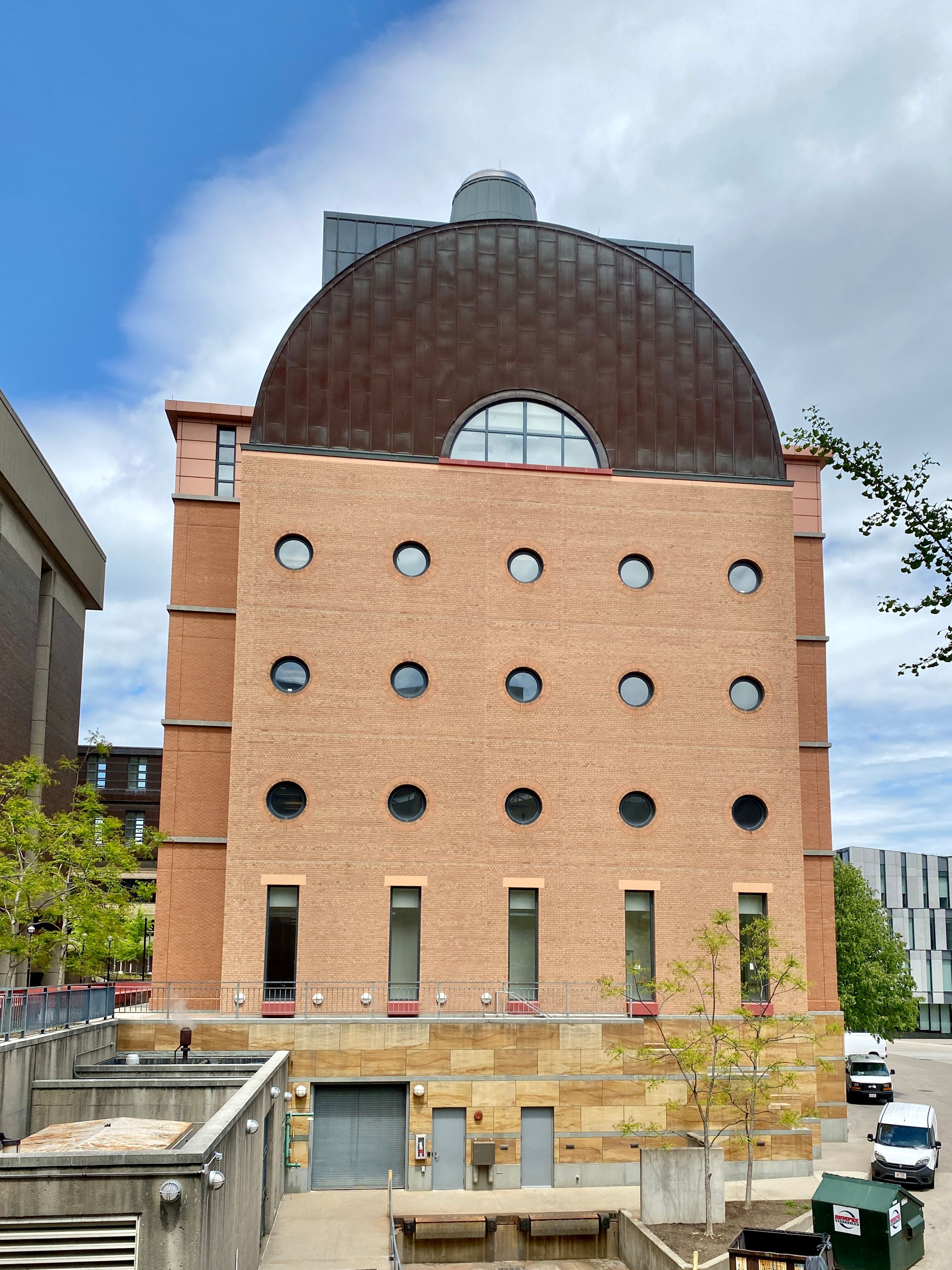 Modern brick building with a distinctive curved, brown roof and circular windows.