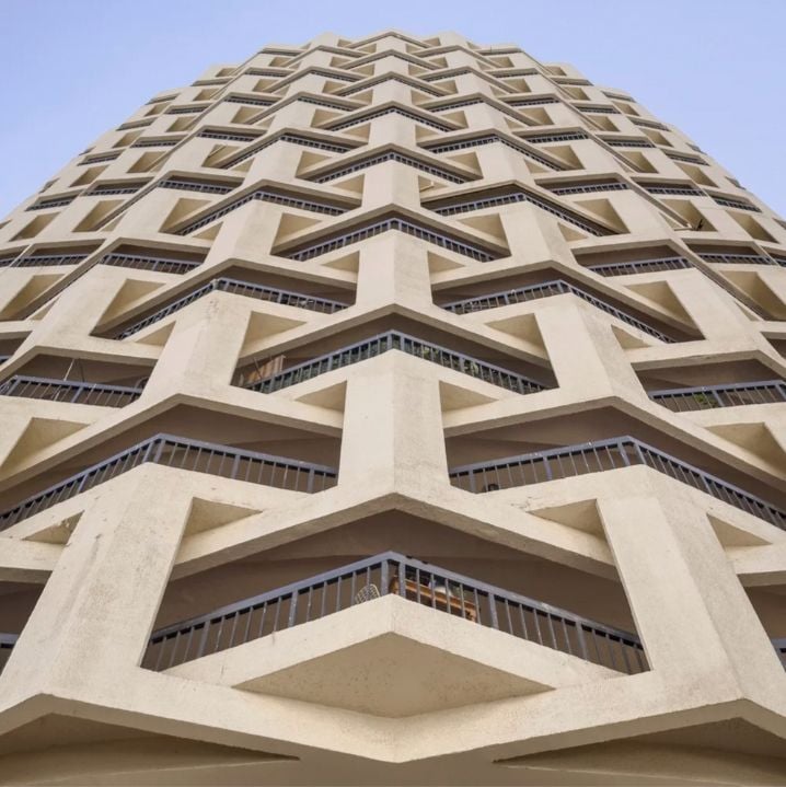 Modern building with intricate geometric patterns stretching towards a clear blue sky.