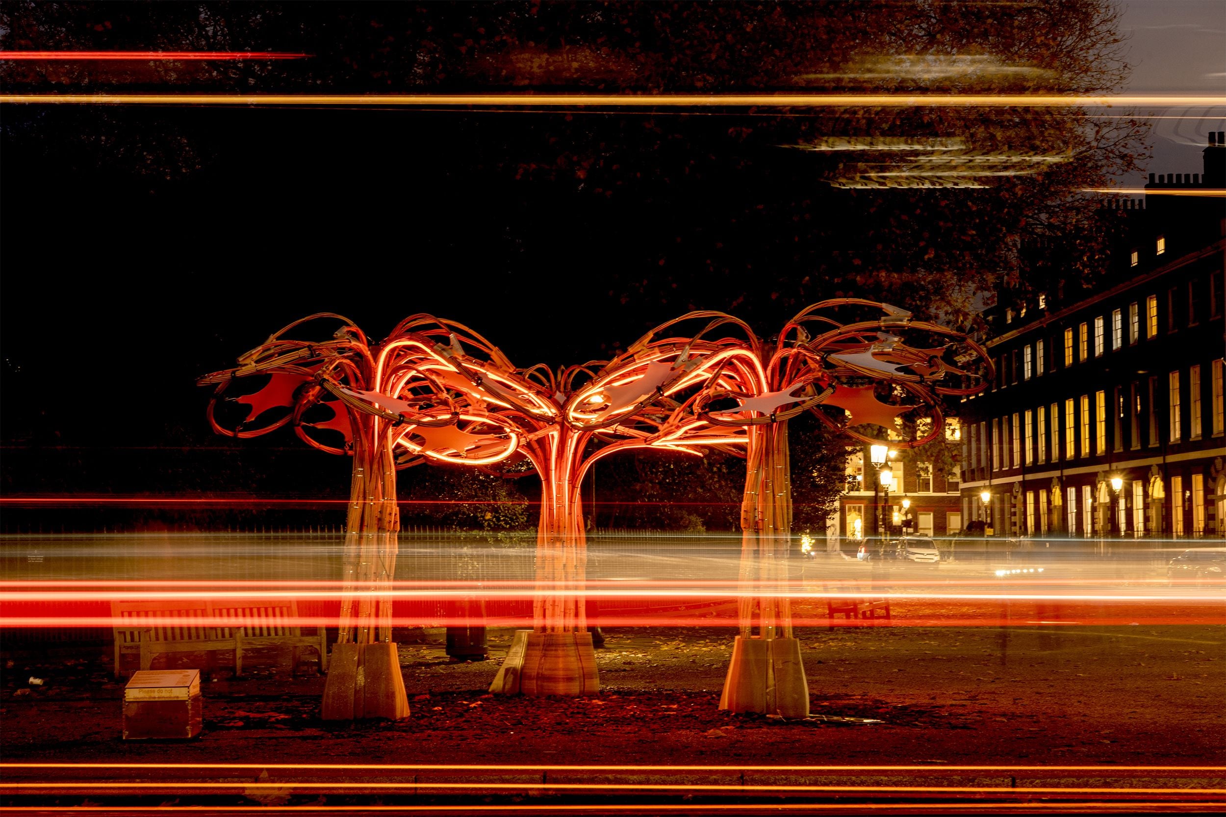 Abstract illuminated sculpture resembling a tree with glowing orange branches at night.