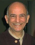 Smiling bald man with a light shirt and dark jacket looking at the camera.