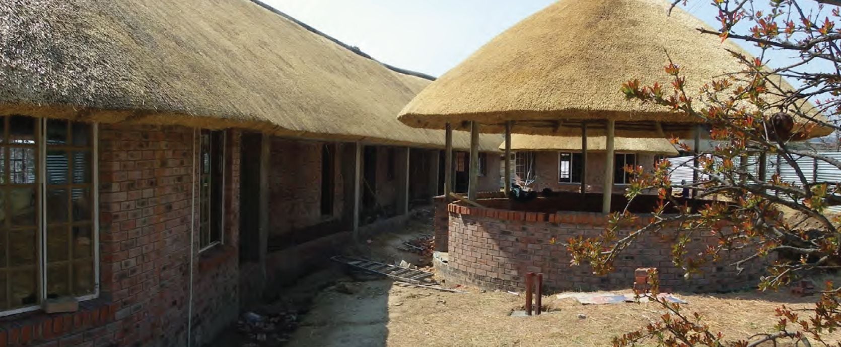Traditional brick buildings with golden thatched roofs and an open-air circular structure.