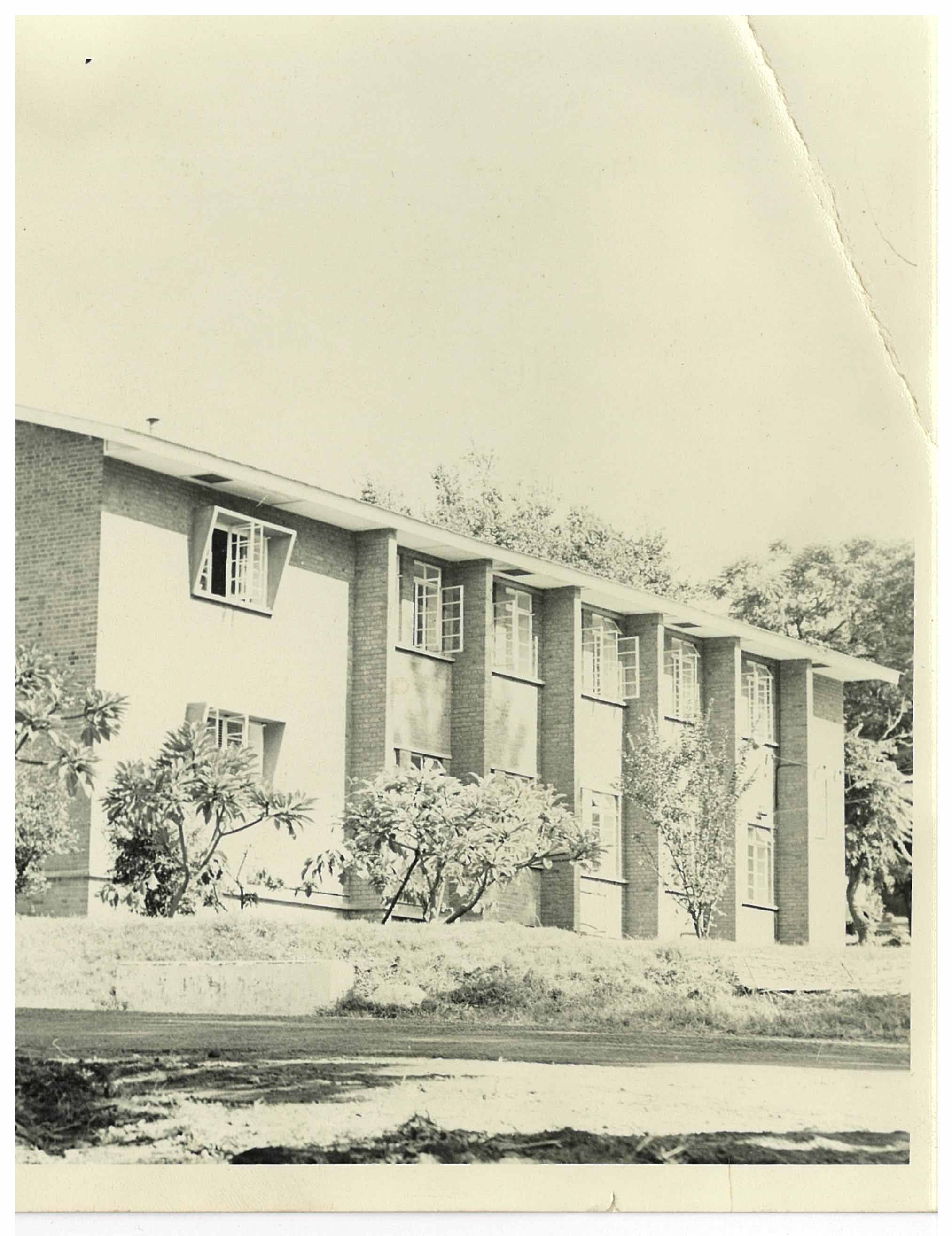 A multi-story brick building with a row of windows and vertical columns.