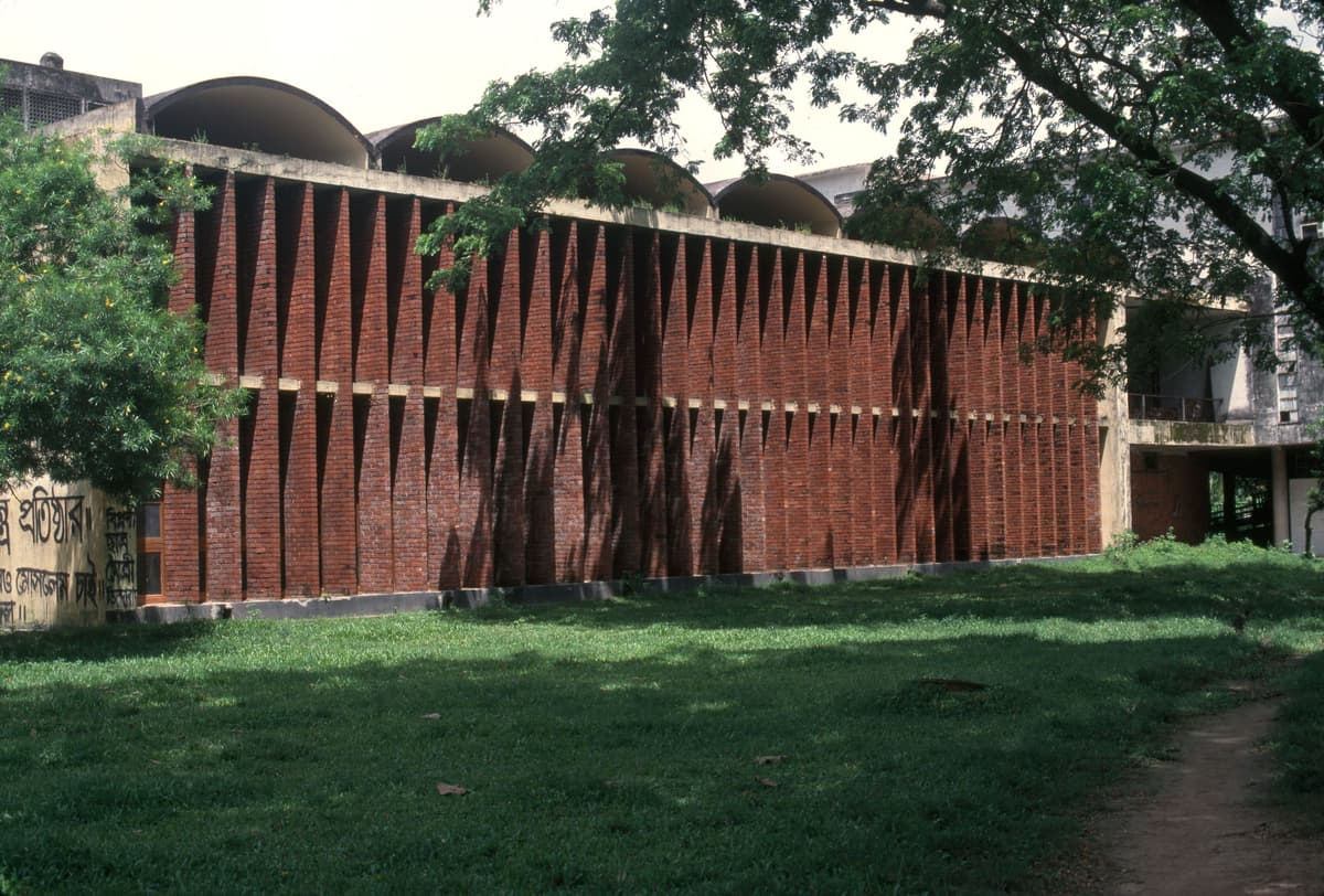 A long, modern building with a facade of vertical brick louvers and domed roof sections.